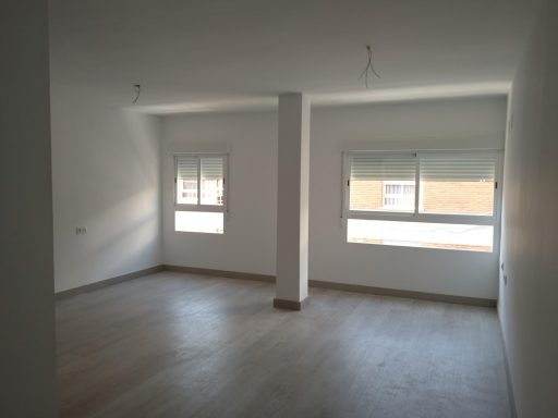 Sala de estar y comedor reformados Habitación vacía con paredes blancas y dos ventanas iluminando el espacio.